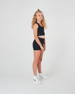 Black bike pants for girls with a high-waisted fit and side pockets, perfect for dance, athletics, netball, and school sports.